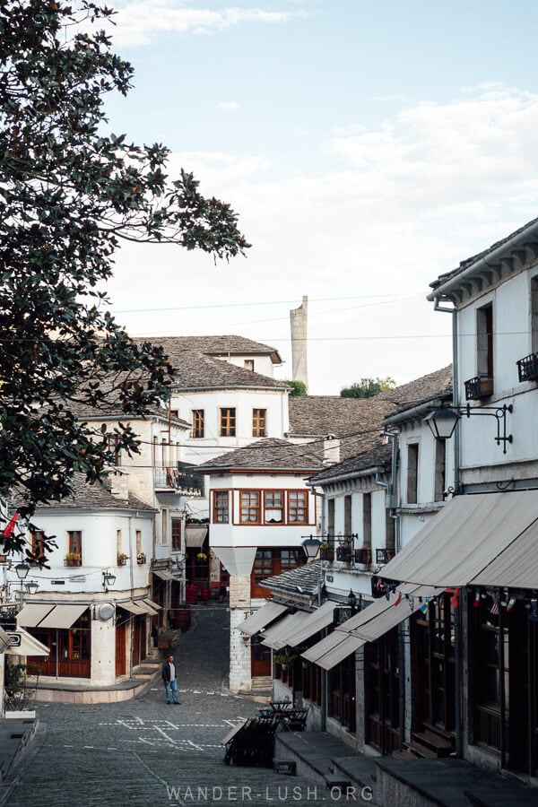 Old houses inside the Gjirokaster Bazaar with the obelisk statue rising up in the background.