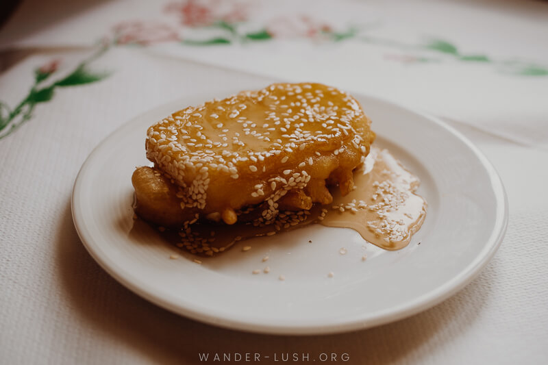 A piece of battered cheese covered with honey and sesame seeds.