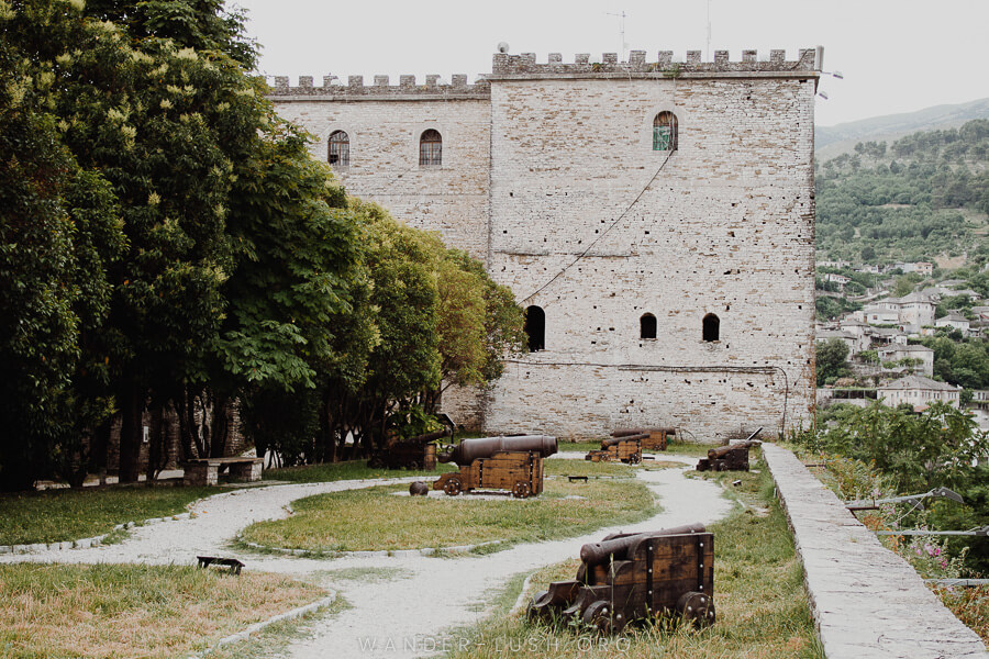 An old stone castle in Gjirokaster with wooden canons out front.