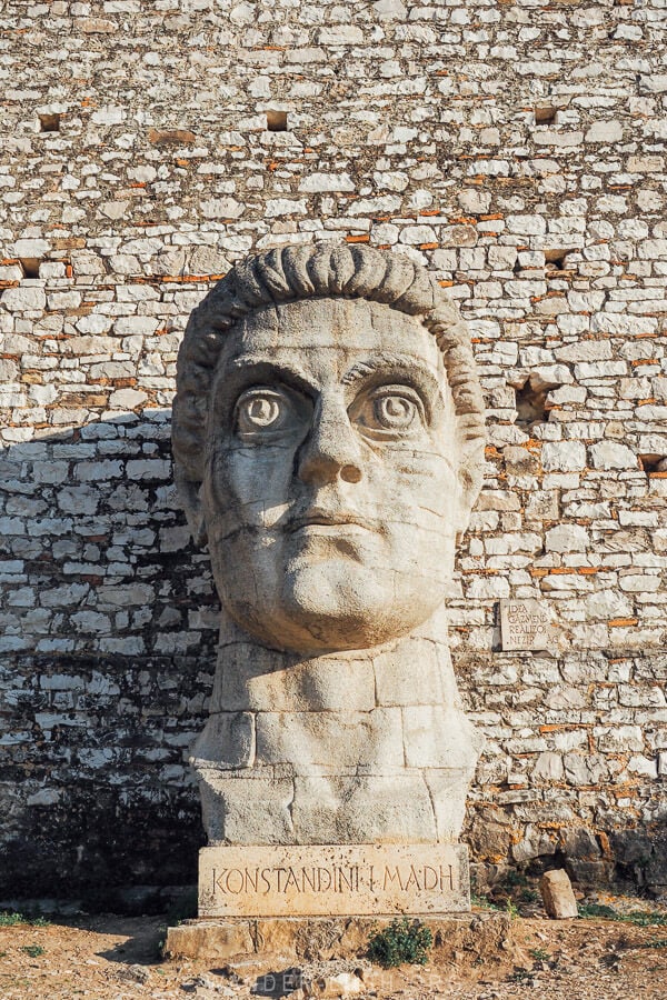 A giant stone head sculpture of Constantine the Great inside the grounds of Berat Castle.