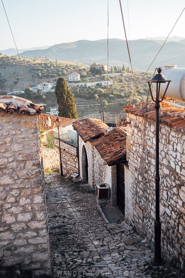 A steep street in Berat, Albania leads down the hill from the castle past stone houses.