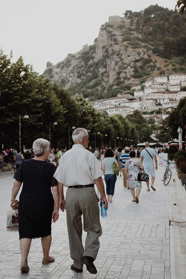 An elderley couple walk along a pedestrian street.