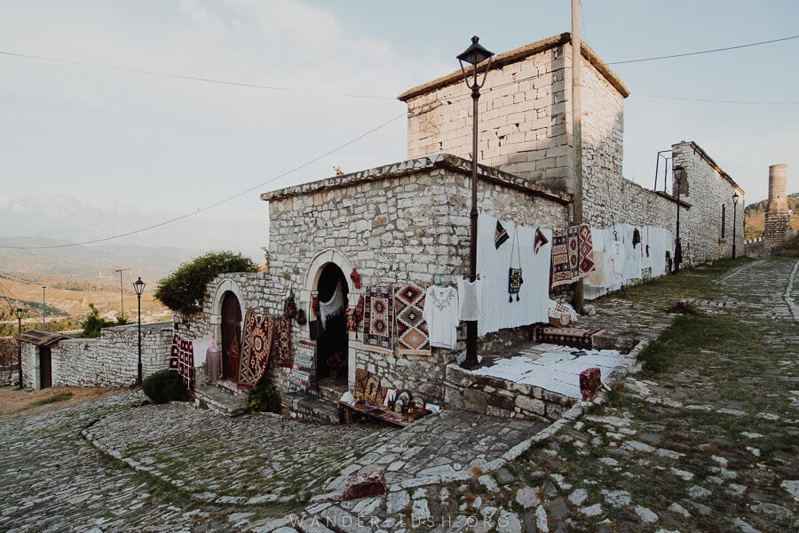 Stone buildings and streets with a display of carpets and clothing.