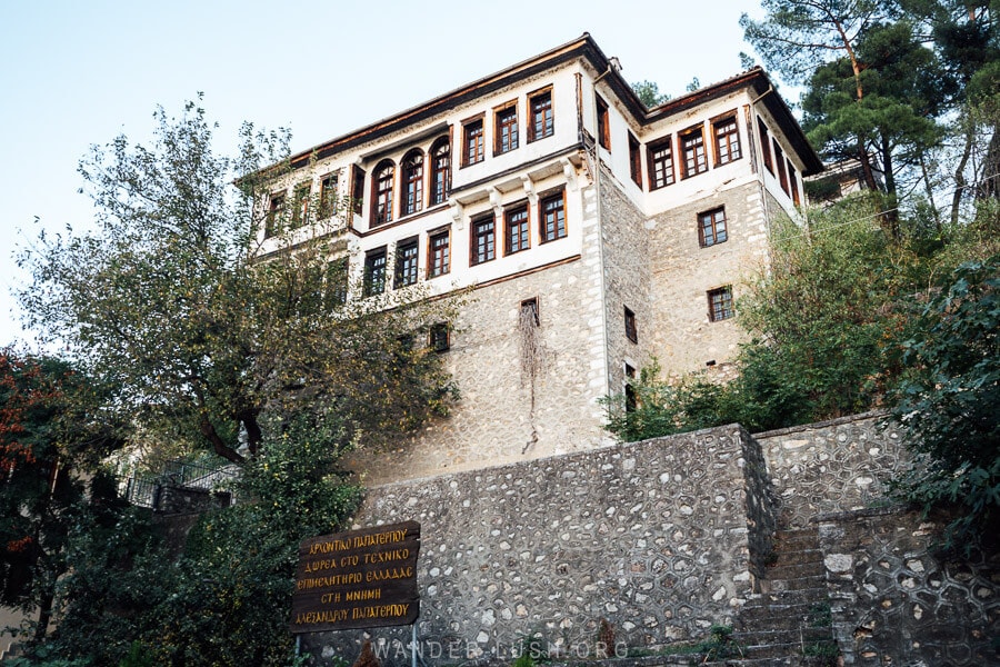 Papaterpou Mansion, a grand house set high on a stone foundation with two levels of wooden windows against a white plaster facade.