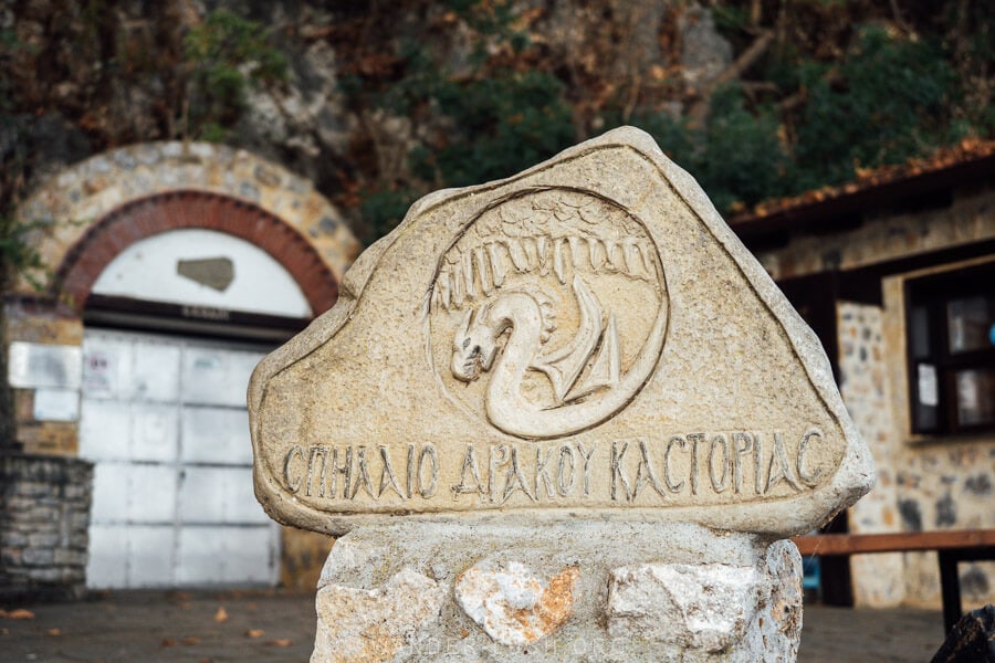 A stone sign marks the entrance to the Dragon's Cave in Kastoria.