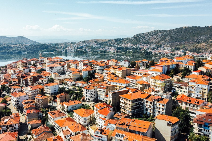 Kastoria city, a sea of red rooftops over the lake, with mountains in the distance.