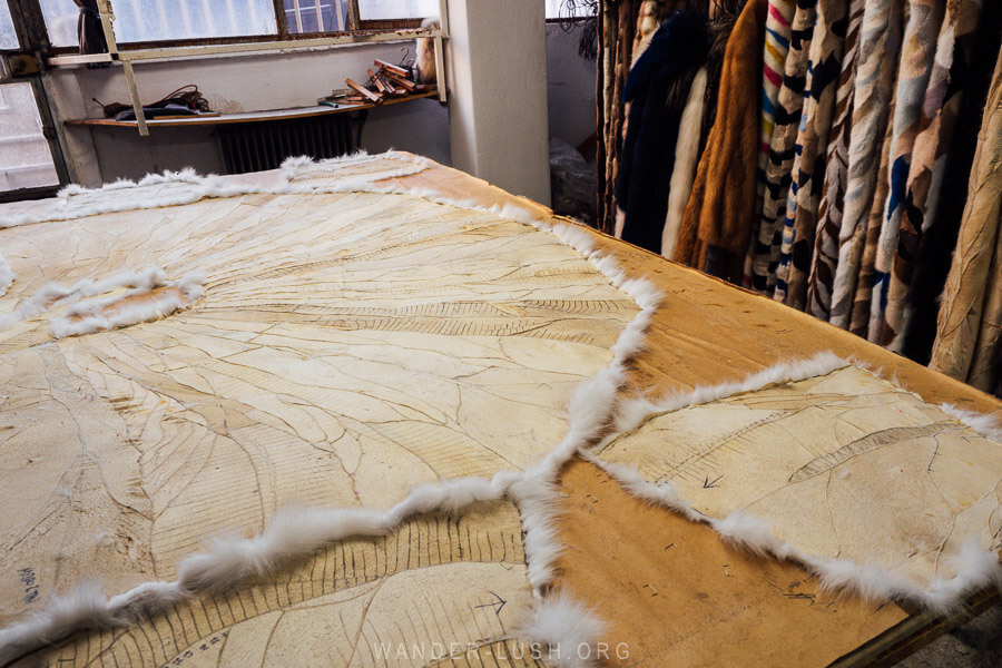 Pattern pieces laid out on a wooden table inside a small fur workshop in Kastoria.