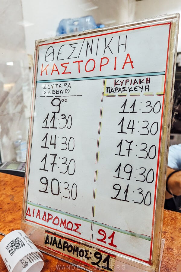 Timetable for buses from Thessaloniki to Kastoria propped up on a ticket counter at the bus station.