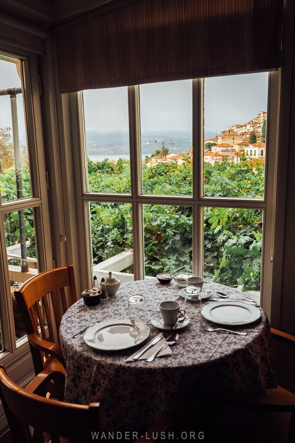 A round table laid out for breakfast overlooking a window with a view of Kastoria city at Venetula's Mansion B&B.