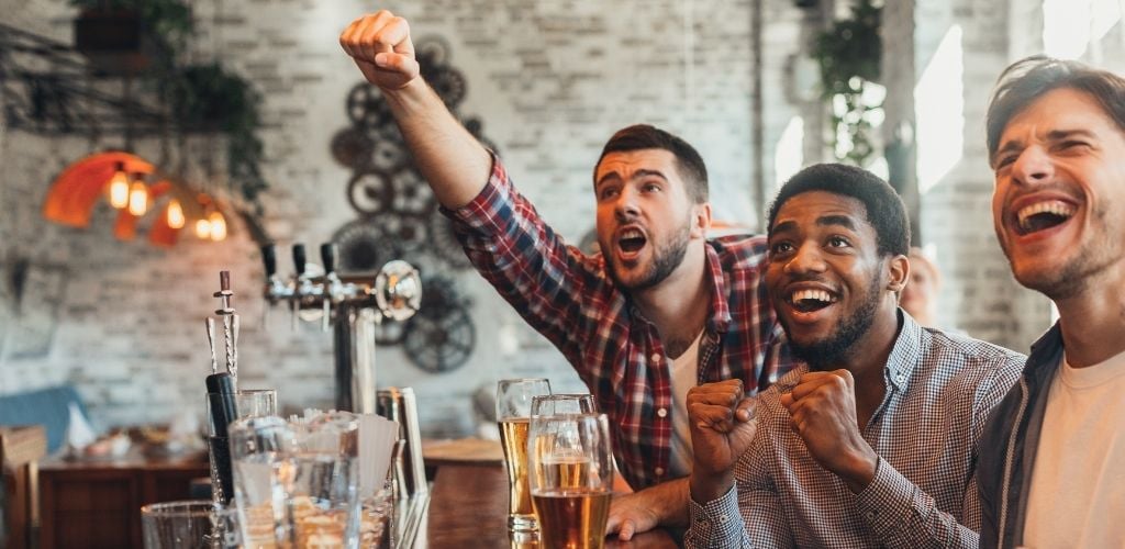 Three man drinking a beer while enjoying watching a sport. 