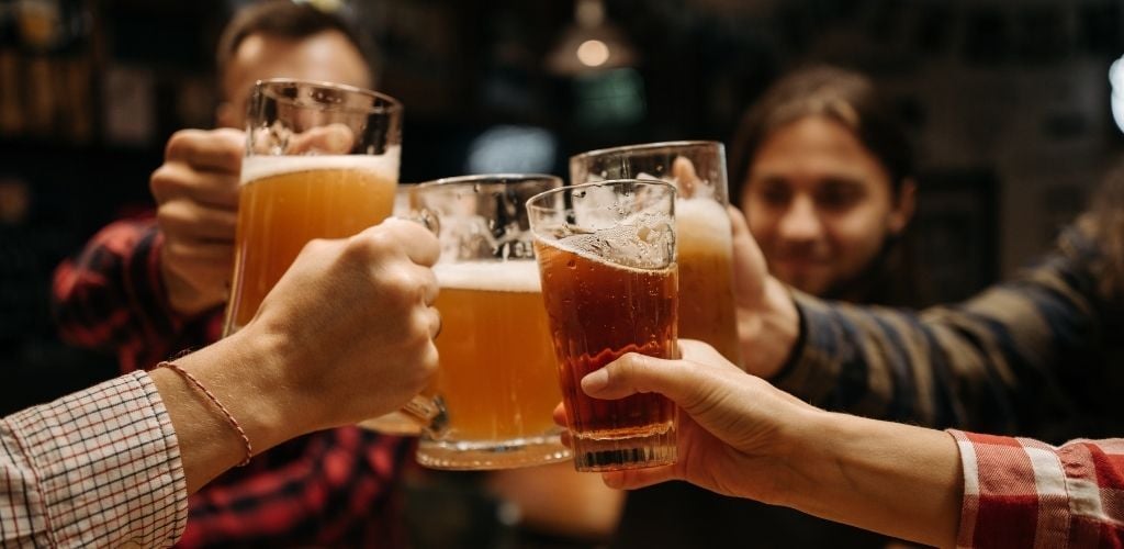 A four group of people toasting a glass of beer. 