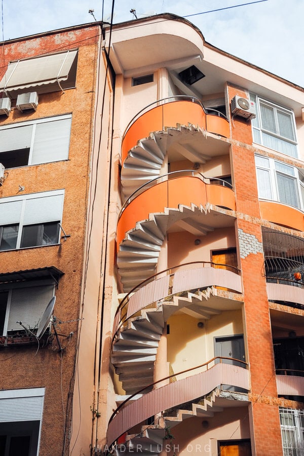A pink and orange staircase on the side of an apartment block in Tirana, Albania.