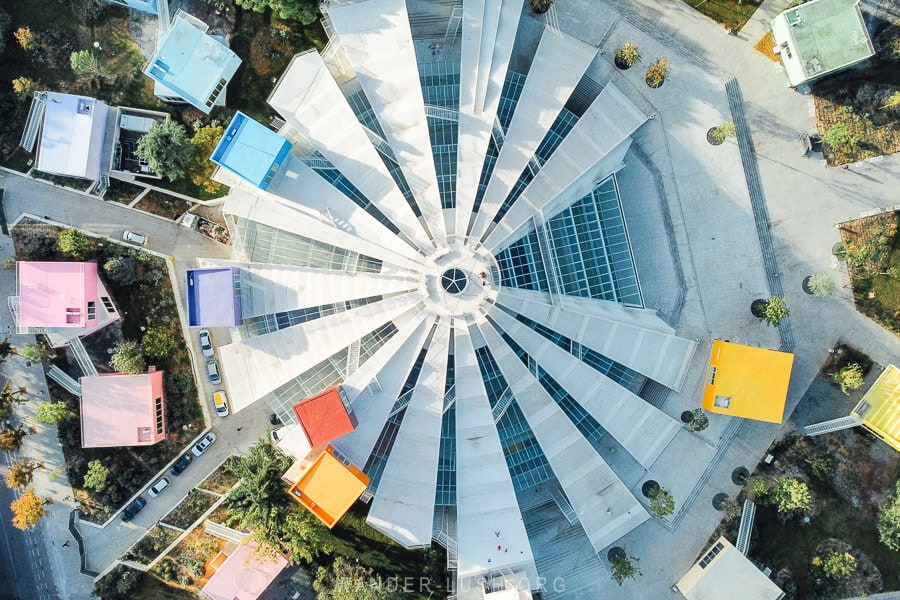Aerial view of the Tirana Pyramid, a refurbished landmark with colourful buildings around it.