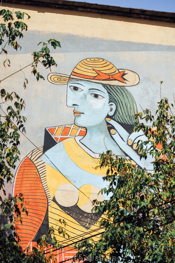 A contemporary Picasso-inspired mural on the side of a building in Tirana depicting a woman with blue skin.