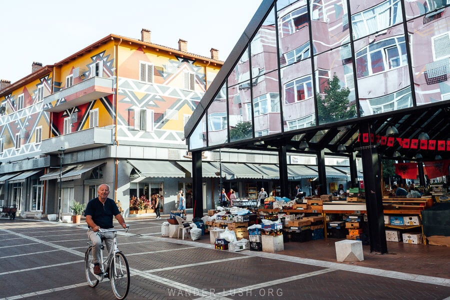 A man rides his bicycle past the covered glass market hall at Pazari i Ri, the new bazaar in Tirana, Albania.