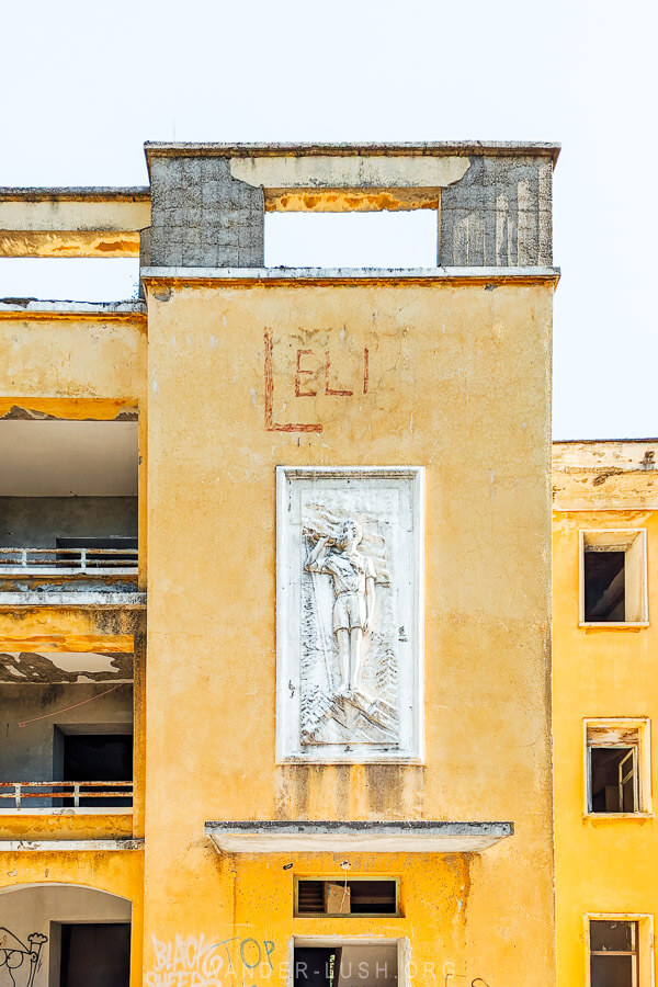 A white frieze depicting a boy scout on an abandoned hotel in Tirana, Albania.