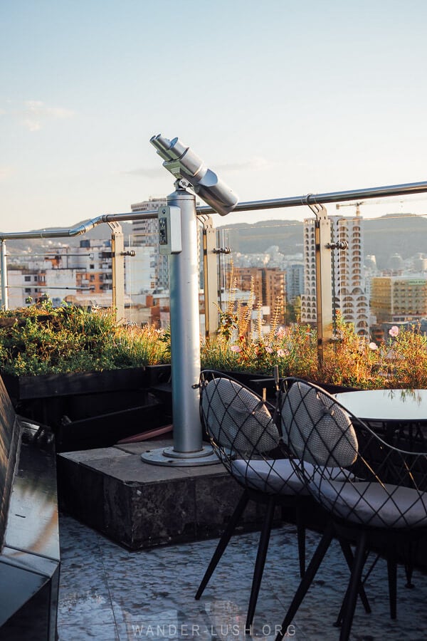 A sky bar in Tirana with a pair of binoculars and outdoor seating.
