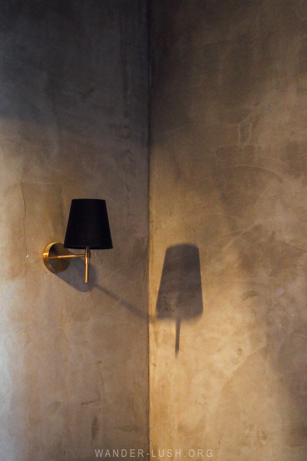 A small black lamp casts a shadow on a textured wall inside a restaurant in Kutaisi, Georgia.