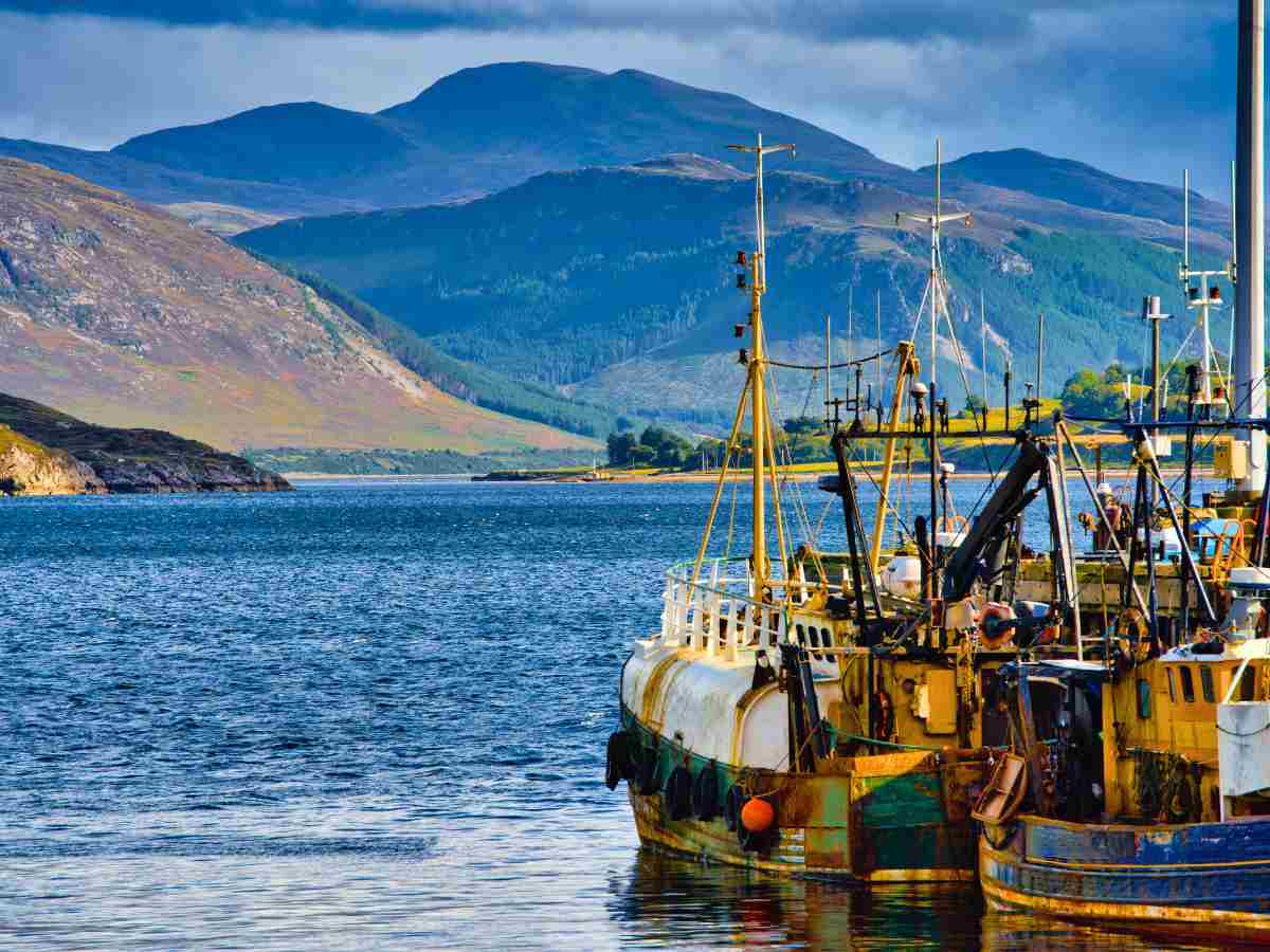 a scenic view of Ullapool fishing boats docked in the harbour and the beautiful mountains surrounding Loch Broom, is truly a mesmerising sight worth visiting, Scotland