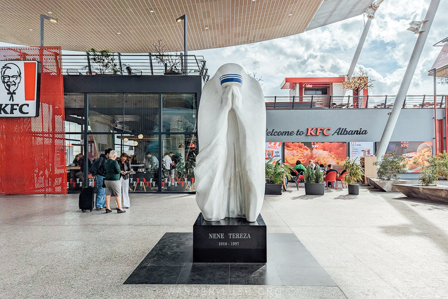 A contemporary statue of Mother Teresa in front of a KFC restaurant at the Tirana Airport.