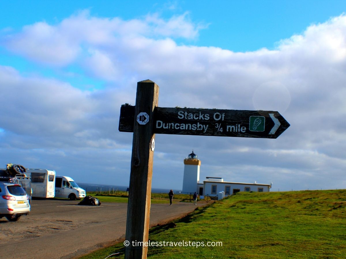 signage to Stacks of Duncansby, car park to the left and Duncansby Lighthouse in the background 