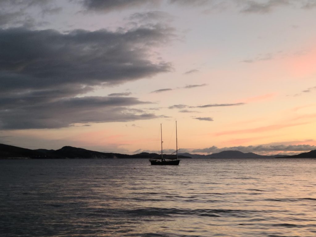 A sailboat at sunset looks painted in the bay of Saranda Albania, our first long stop in our gap year.