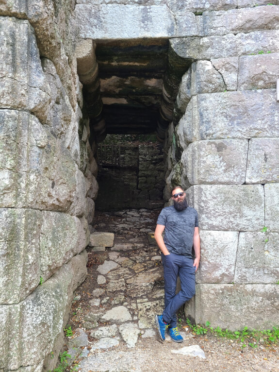 Man poses at the Lake Gate at Butrint National Park. A deep entrance into hellenistic fortifications.