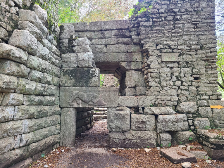 The Lion's Gate at Butrint National Park. A stone gate with a carving of a lion over a wild boar.