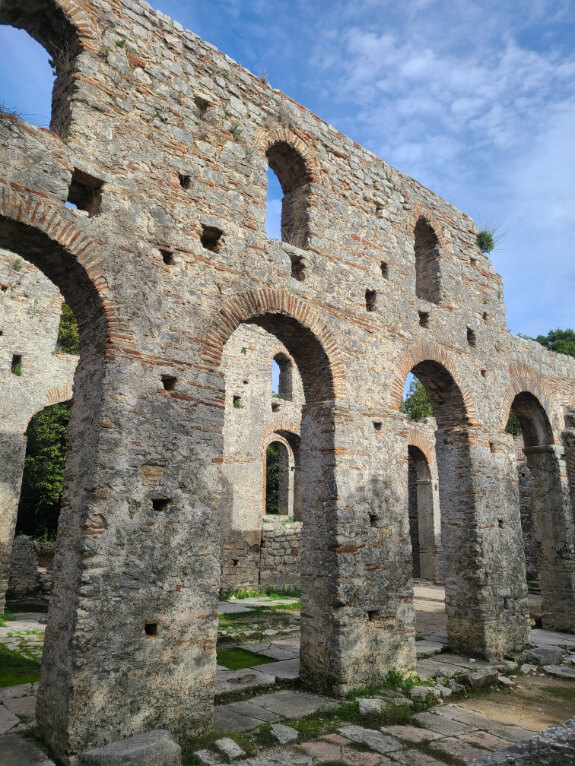 Ruins of two storey walls of the great basilica at Butrint National Park with a blue sky high above.