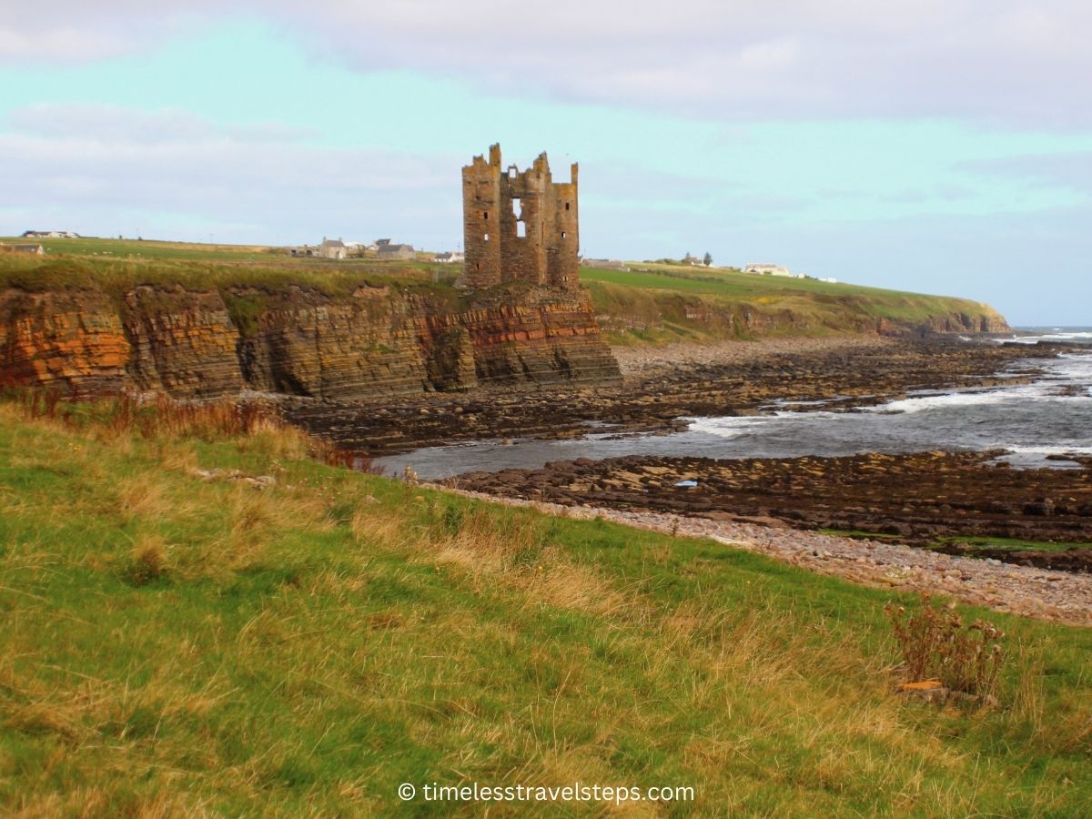 Old Keiss Castle coastal walk Caithness: a splendid view of the beautiful castle ruins on a cliff viewed from a distance during the coastal stroll. | timeless travel steps