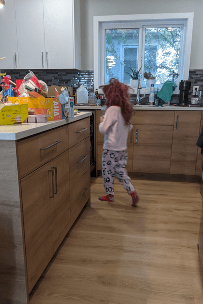 A scraggly tot wanders through a disorganized kitchen