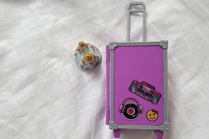 A barbie suitcase and a small basilica figurine.