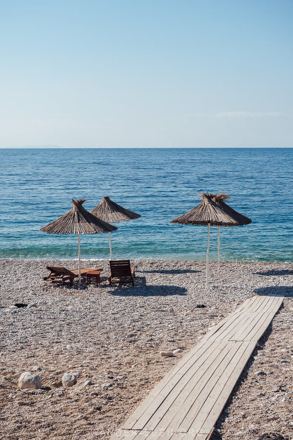 A beach in Albania with thatched umbrellas.