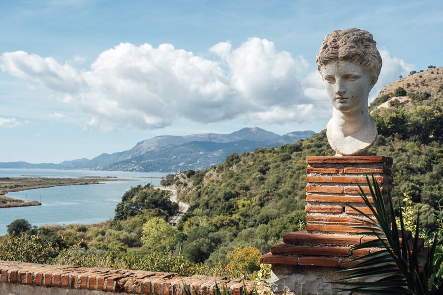 A statue in front of a landscape of sea and greenery in Butrint National Park, Albania.