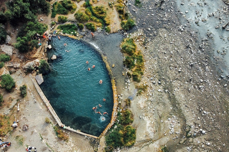 An aerial view of a tear-shaped natural sulfur swimming pool in Benja, Albania.