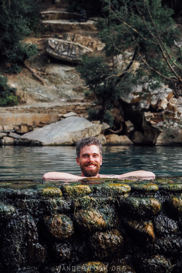 A man leaning on the edge of a thermal pool at the Benja Hot Springs in Albania.