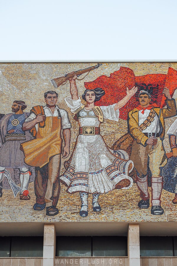 A colourful mosaic in Tirana, Albania depicting different characters from history and a black and red Albanian flag.