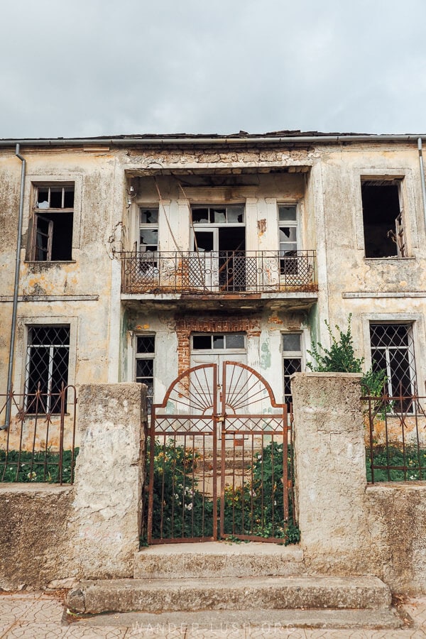 An old abandoned house in Leskovik, Albania with a beautiful wrought iron gate.