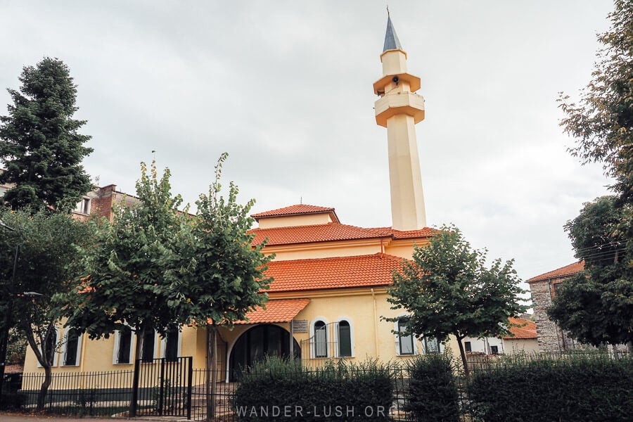 The Leskovik mosque, a small lemon-coloured mosque with a new roof and tall minaret.