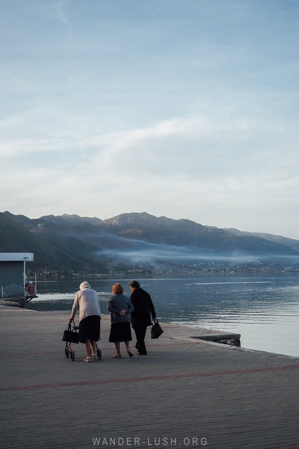 Three ladies walk along the shore of Lake Ohrid in Pogradec at dusk.