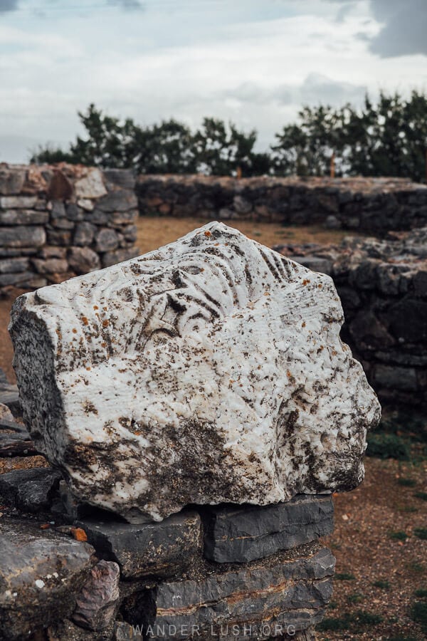 A fragment of engraved rock perched on a stone wall in Lin, Albania.