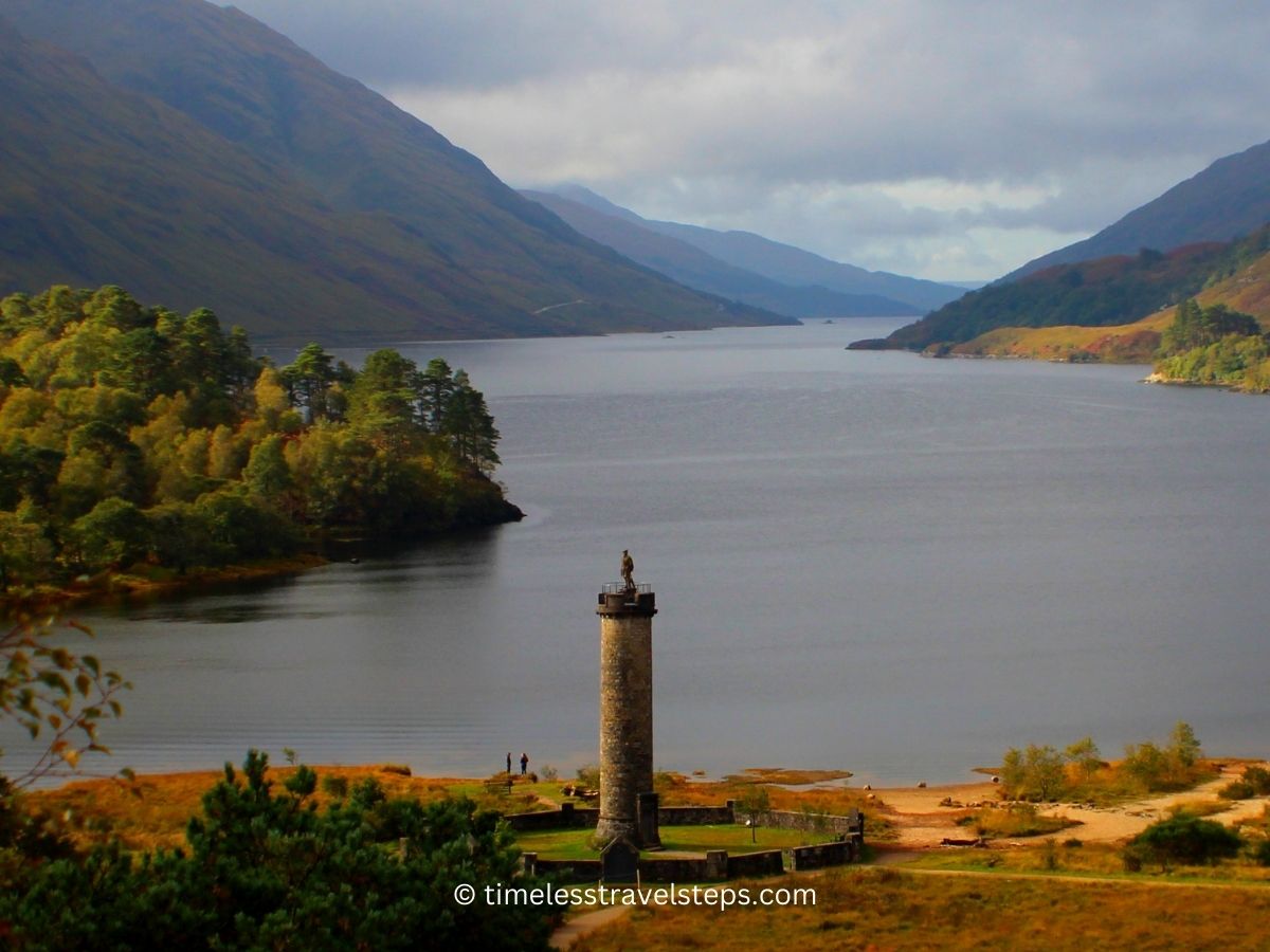 glenfinnan monument overlooking the serene Loch Shiel on a hazy autumn's day golden hues