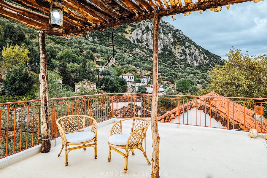 Two chairs arranged under a wooden canopy on a hotel rooftop terrace in Qeparo, Albania.