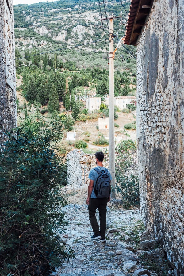 A man walking down a stone laneway in a traditional village in Albania.