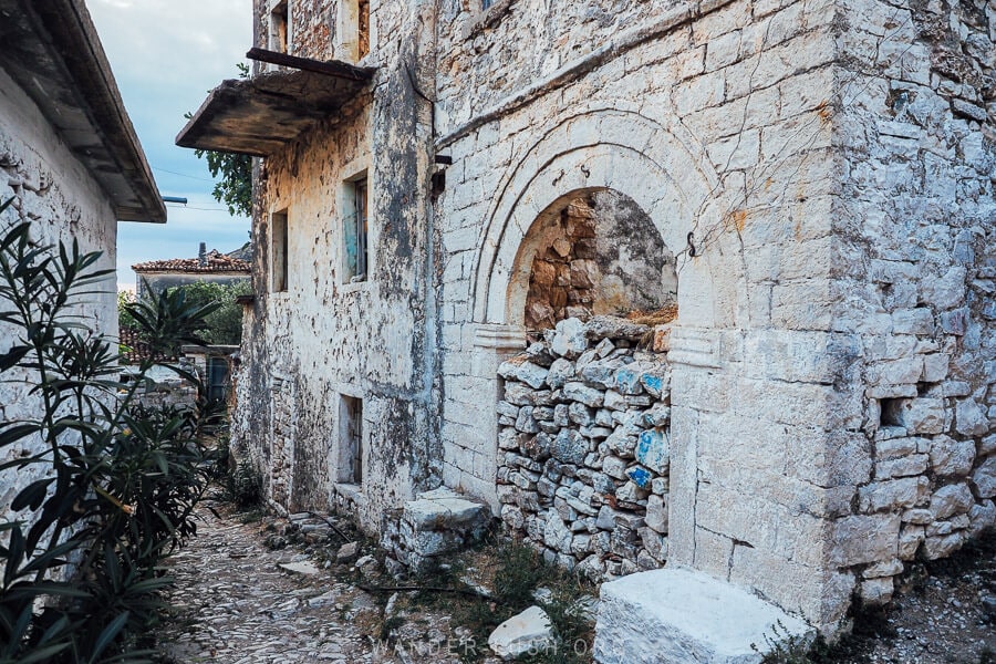 An abandoned stone house in Qeparo, Albania with rocks placed in the arched doorway.