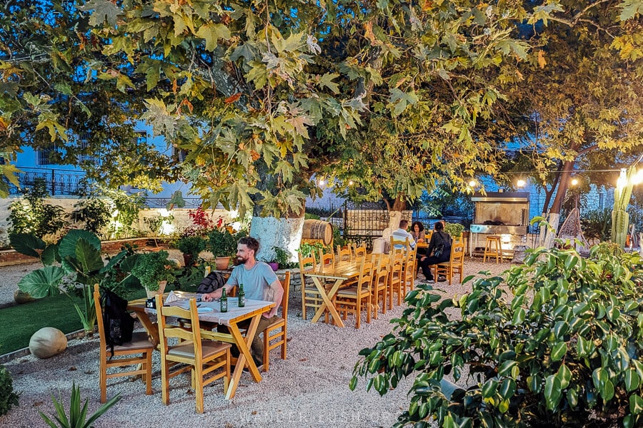 A man drinks beer under an oak tree at a small restaurant in Upper Qeparo, Albania.