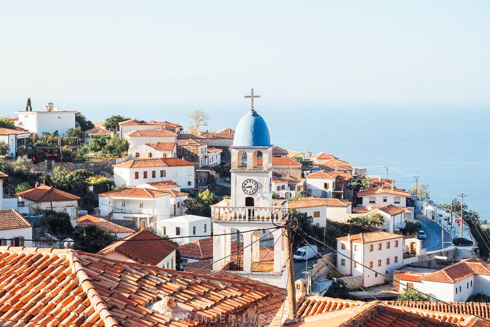 A blue dome on a white church tower pictured against the sea in the village of Dhermi Albania.