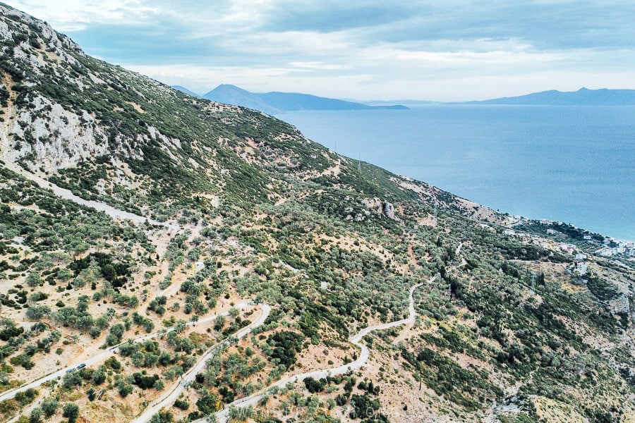 A white road curls around a mountainside linking upper and lower Qeparo villages in Albania.