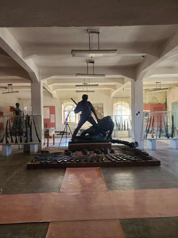 A statue commemorating WWII amongst a display of guns from the time