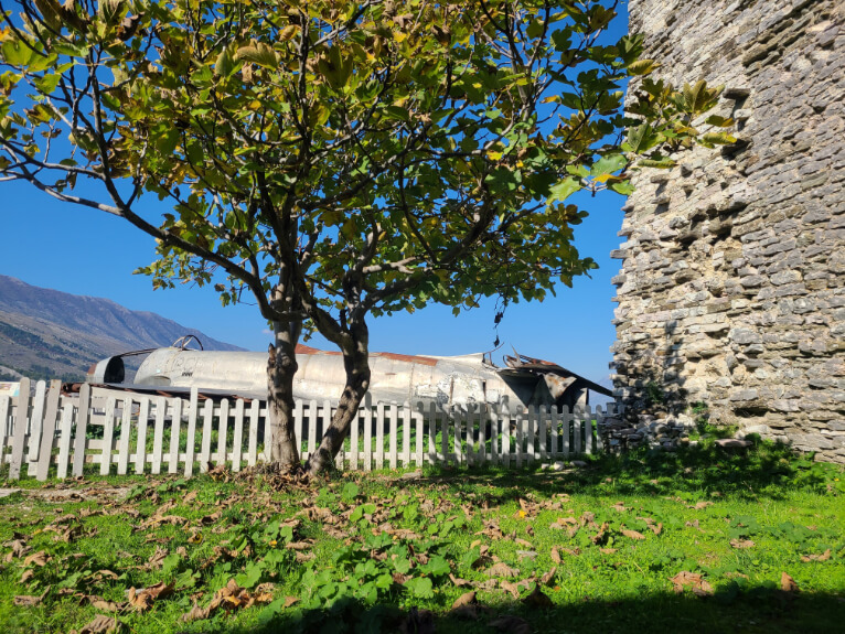 The wreckage from a plane sits behind a tree below a wall at Gjirokaster Castle